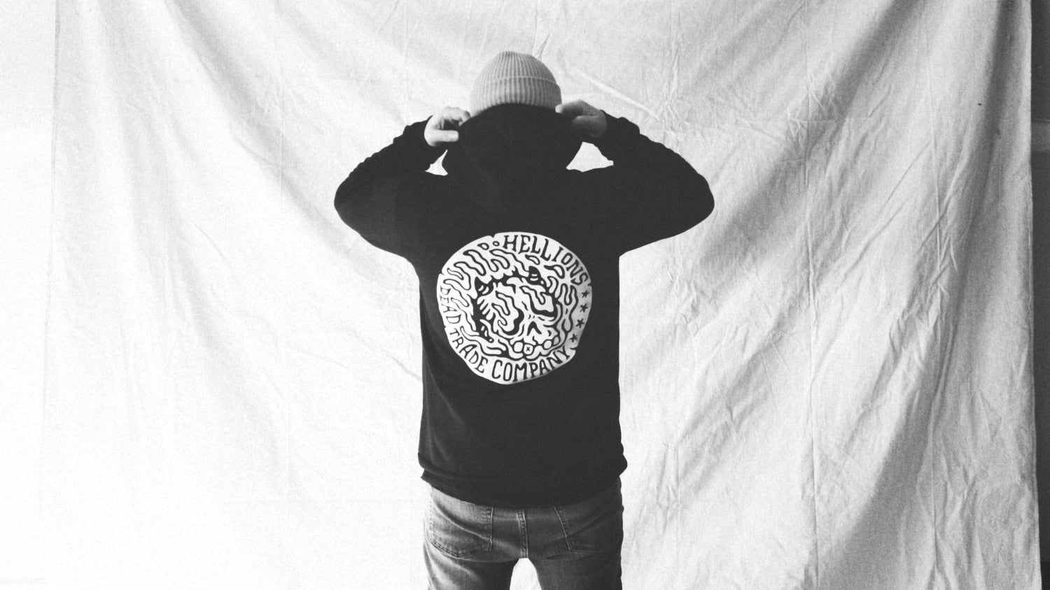 Black hoodie with a flaming devil skull screen printed in white on the back.
