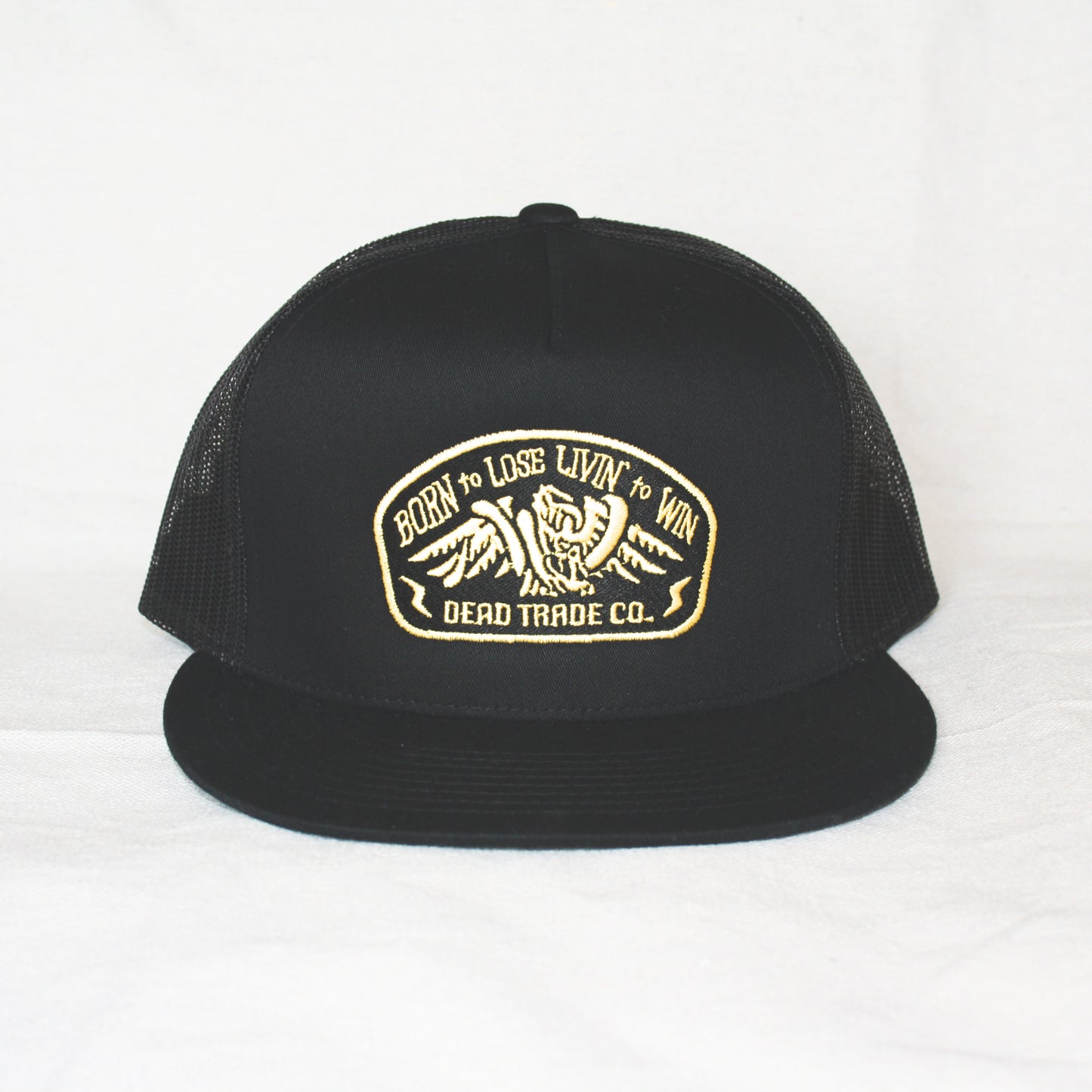 Black snapback with 'Born to Lose' gold embroidery on the front panel. High-profile, flat-brim trucker cap with breathable mesh. Made of 65% polyester, 35% cotton. Structured 5-panel, 4” crown. Finished in Alberta, Canada.