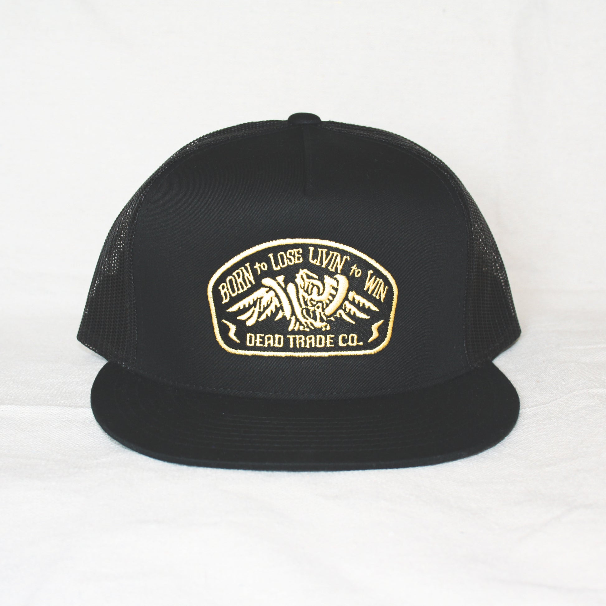 Black snapback with 'Born to Lose' gold embroidery on the front panel. High-profile, flat-brim trucker cap with breathable mesh. Made of 65% polyester, 35% cotton. Structured 5-panel, 4” crown. Finished in Alberta, Canada.