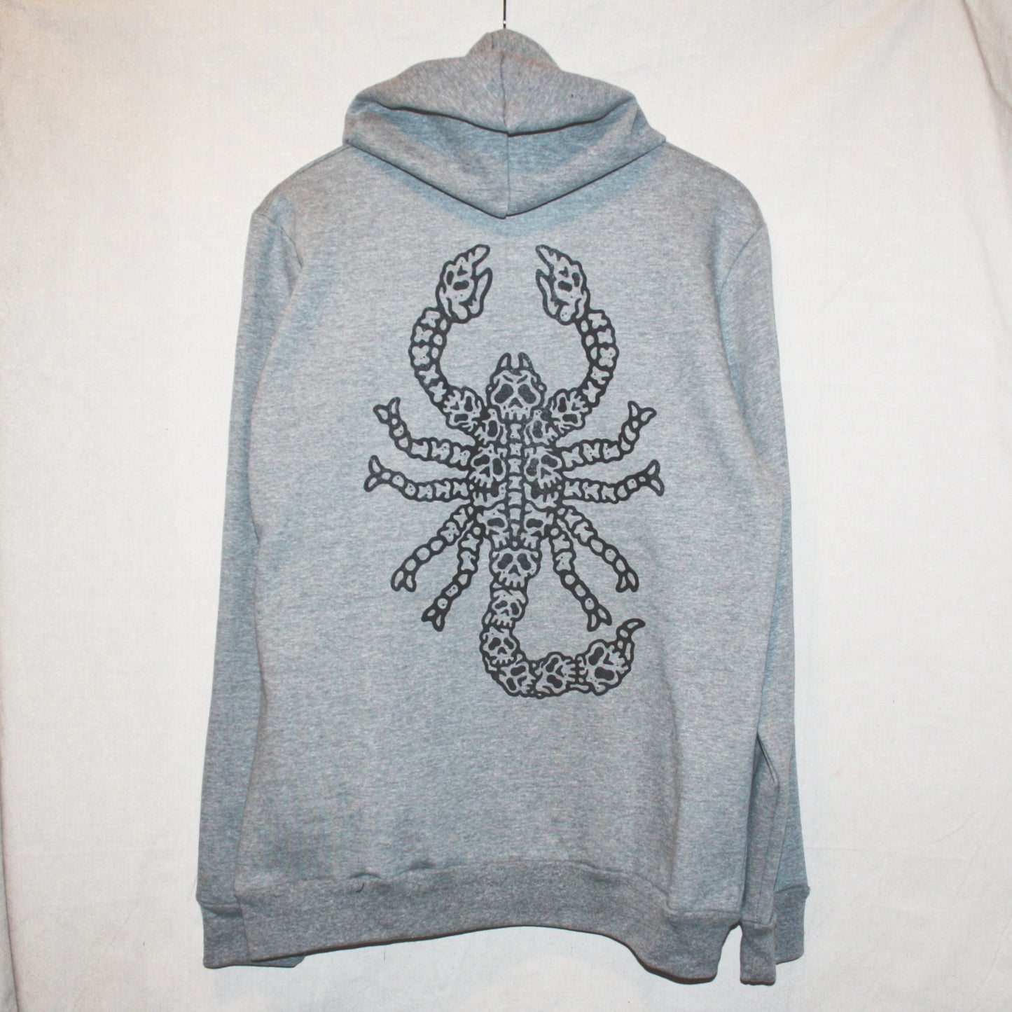 Grey colour, high-quality, made-in-Canada hoodie featuring a hand-drawn scorpion made of skulls screen printed in black on the back. Crafted with 50/50 ring-spun poly/cotton fleece, soft feel, reduced pilling, and durability. Unisex size, 14oz, perfect for cold Canadian winters.