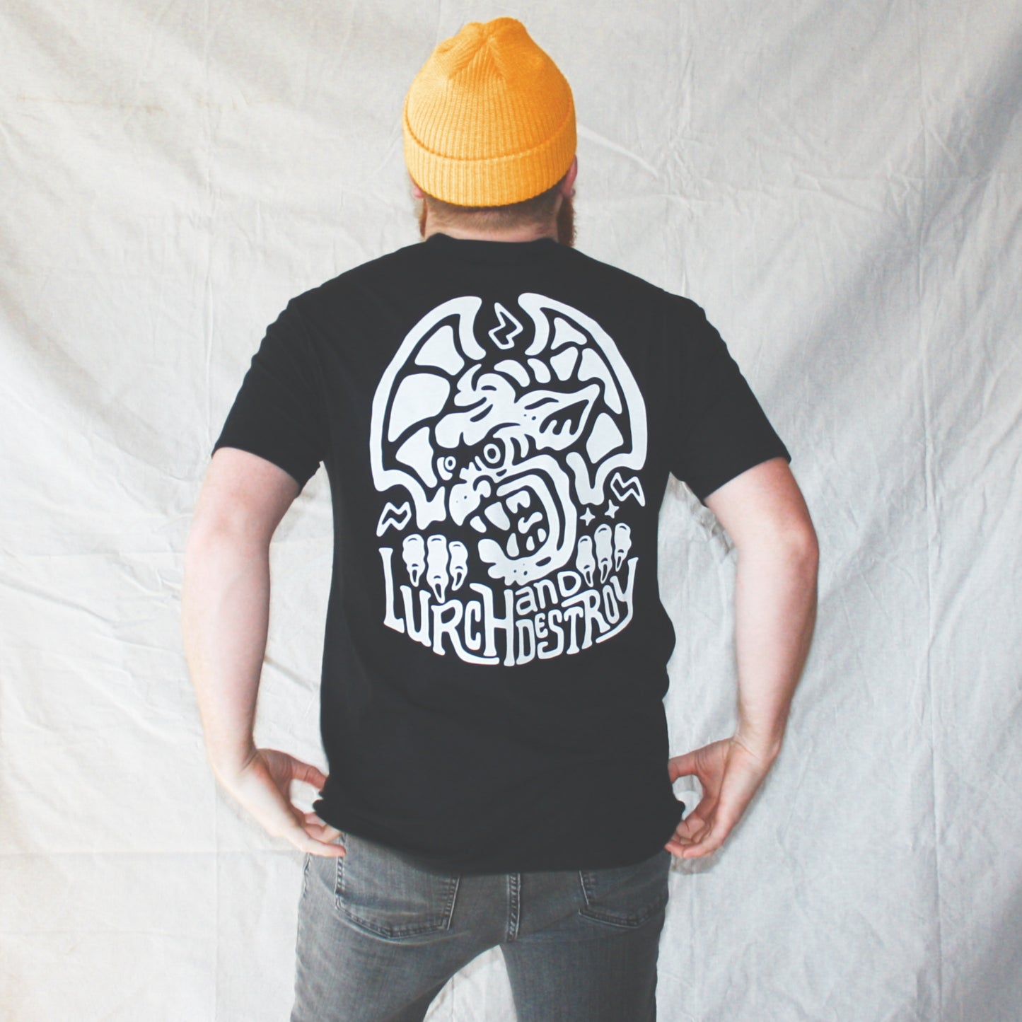 Black graphic t-shirt made in Canada from a soft 100% ring-spun cotton, featuring a bold hand-drawn design of an angry gargoyle growling over the words “lurch and destroy,” screen printed in white ink. Perfect for those who appreciate lowbrow, horror-inspired artwork.