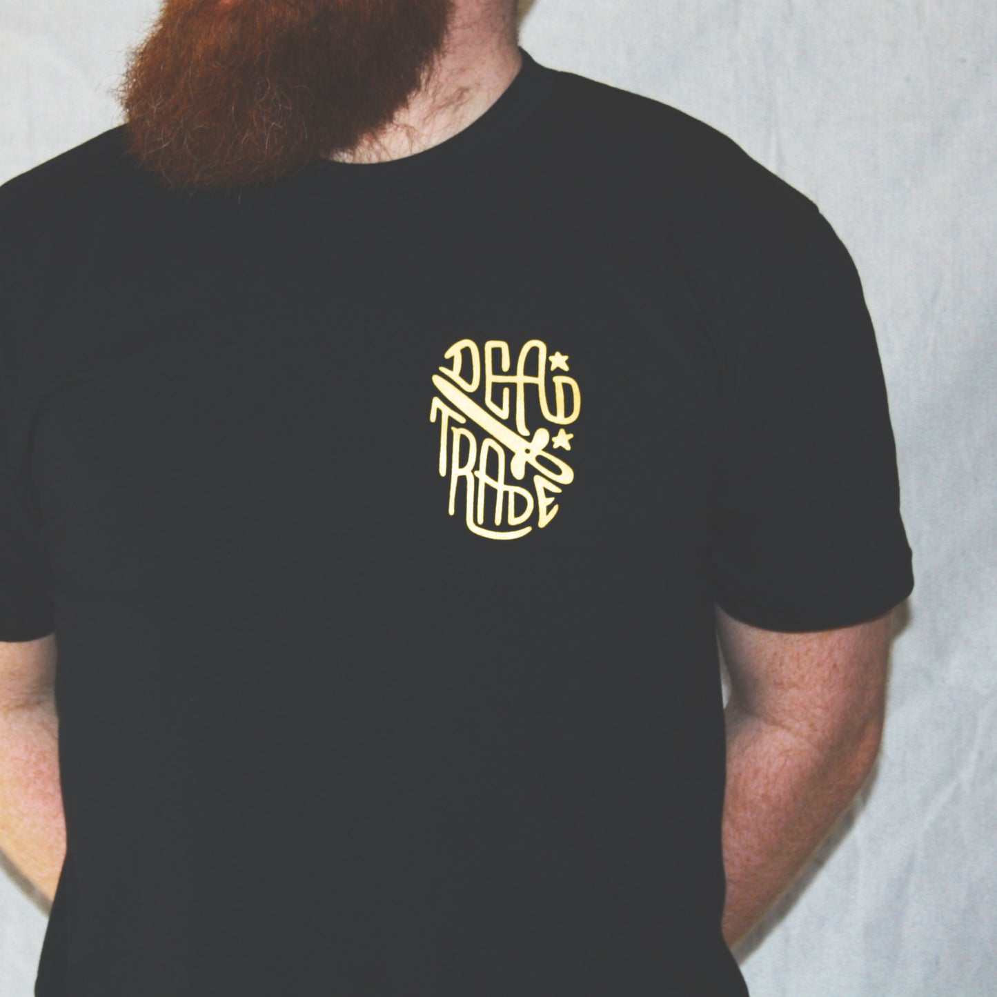 Black graphic t-shirt made in Canada from a soft 100% ring-spun cotton, featuring a bold hand-drawn design of a smiling skeleton holding a switchblade with the words “stay gold,” screen printed in yellow ink. Perfect for those who appreciate lowbrow, edgy artwork.